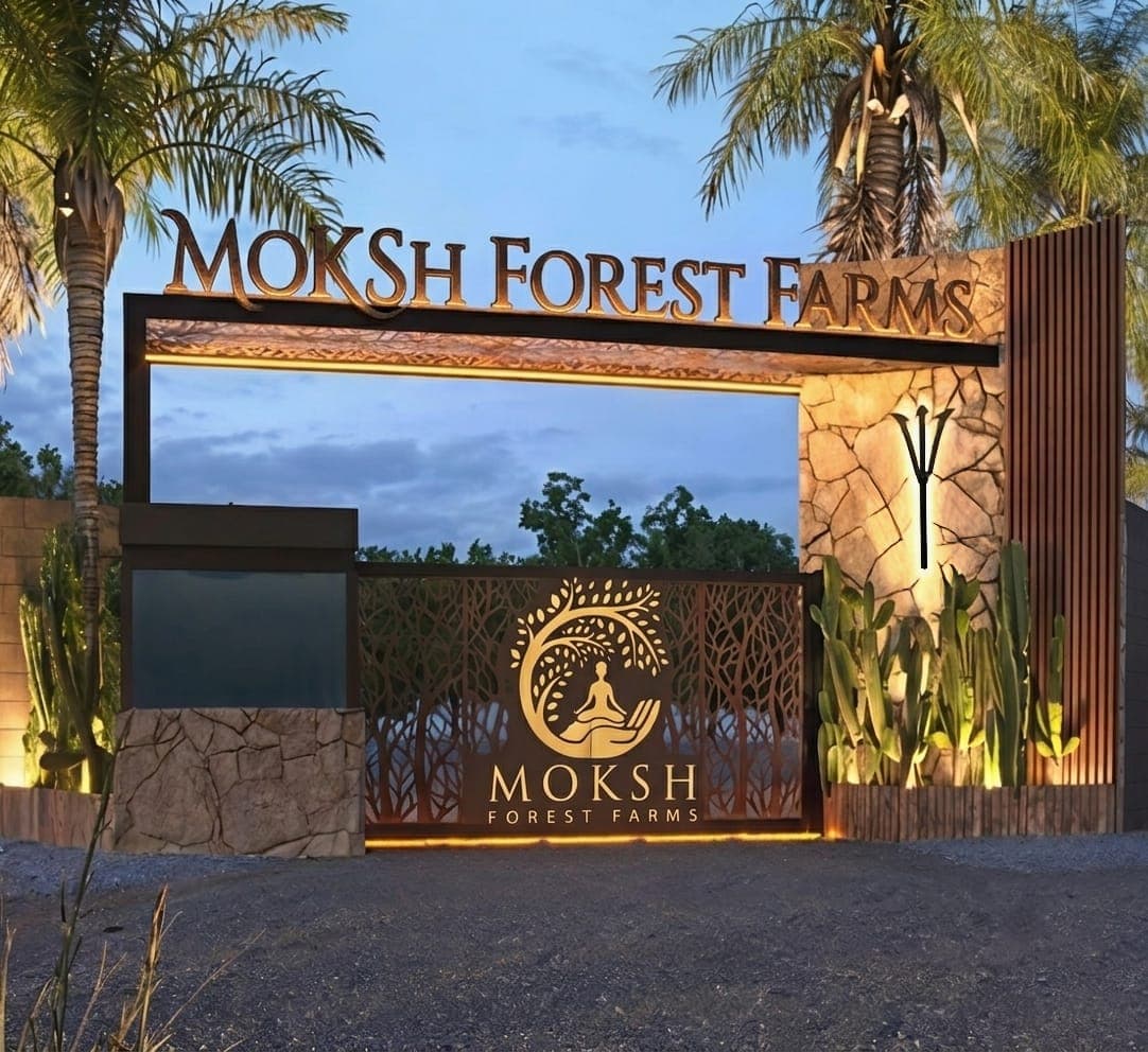 The lit entrance gate to Moksh Forest Farms at dusk, framed by palms