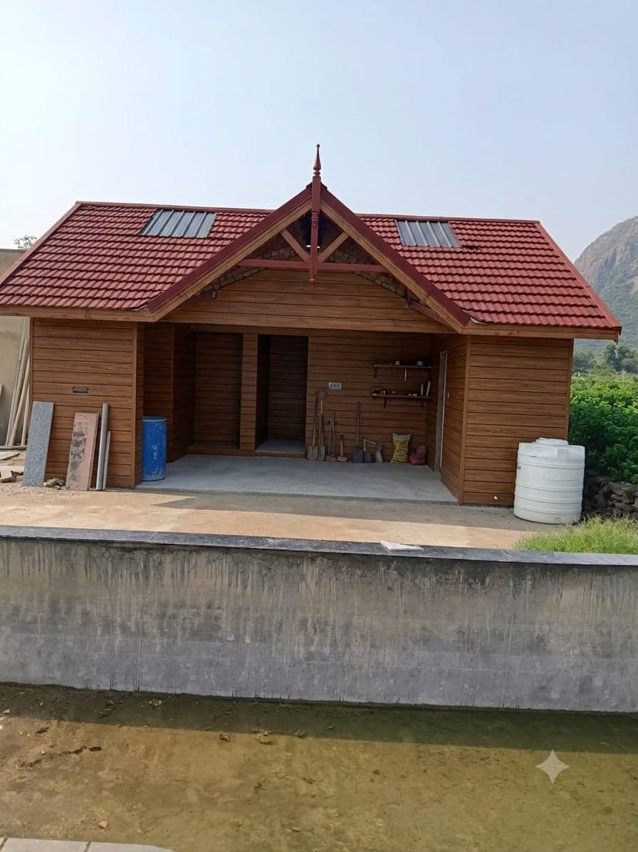 A completed timber farmhouse with a tiled pitched roof, the Aravalli hills rising behind it